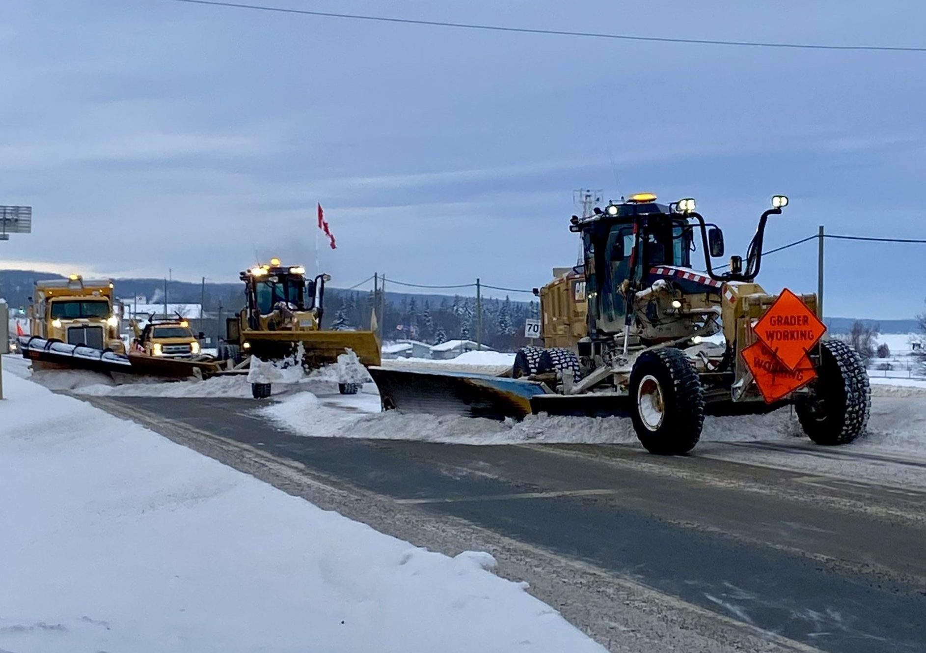 Snowplows and graders clearing snow from a highway in winter conditions.