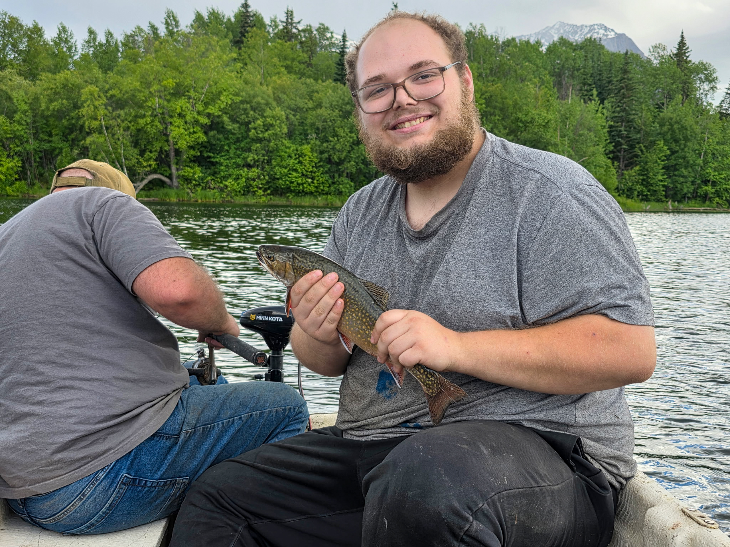 Anthony Flynn holding a fish on a boat on a lake.