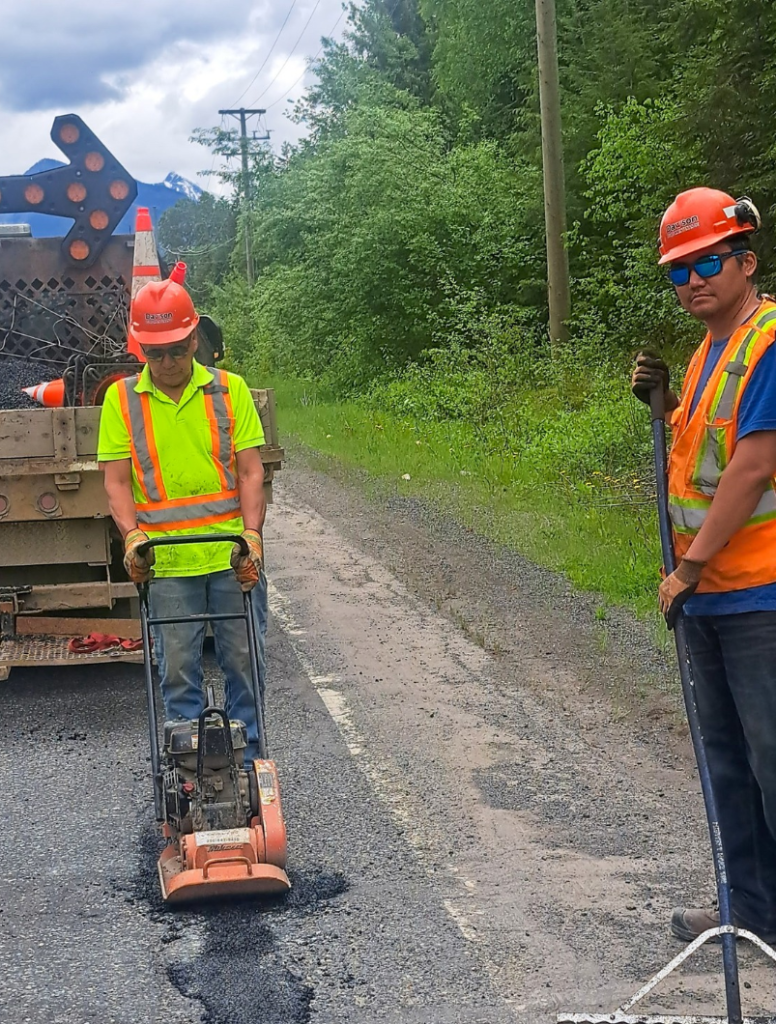 Mike Morrison and Billy Gunanoot, Dawson Road Maintenance crew members, conducting pothole patching on a road in Carnaby, British Columbia